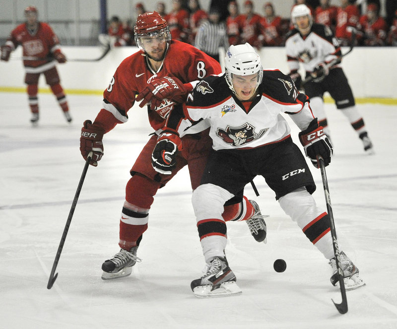 Phil Lane of the Pirates tries to control the puck against Antoine-Houde Caron of the University of New Brunswick.
