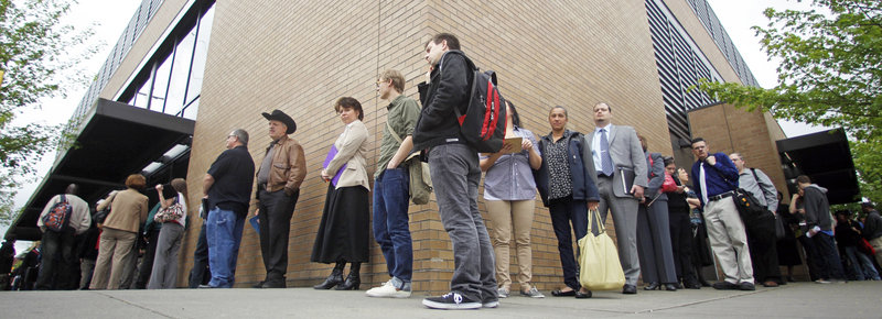 Job seekers wait in line during a job fair in Portland, Ore., in April. A decline in the U.S. unemployment rate drew skeptical reactions Friday.