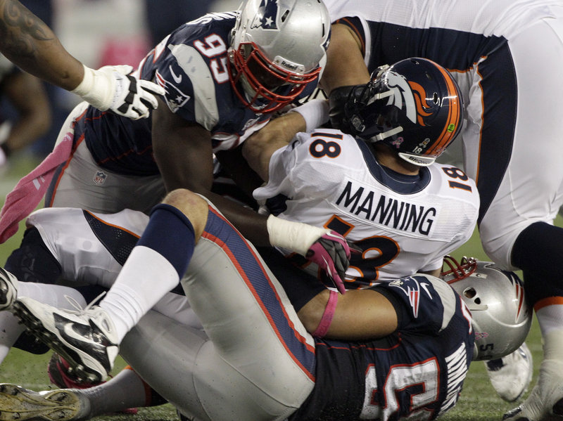 Rob Ninkovich, bottom, sandwiches Denver quarterback Peyton Manning, forcing a third-quarter fumble with the help of rookie defensive end Chandler Jones.