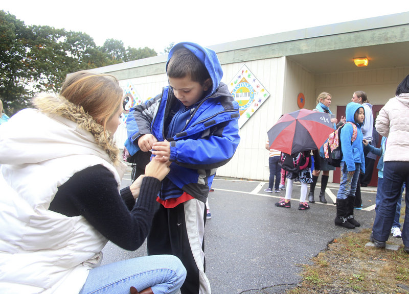 Amanda McGuire helps her son Kody, 6, a first-grader, zip his coat after his first day back at Hall Elementary School in Portland on Tuesday. A fire on Sept. 17 closed the school for three weeks.