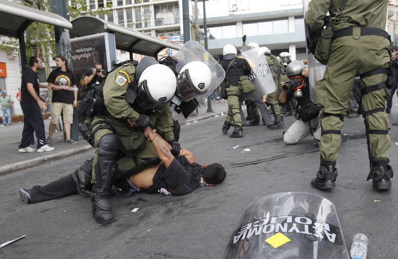 A demonstrator is arrested Tuesday in Athens, one of 200 detained in protests during Angela Merkel’s visit.