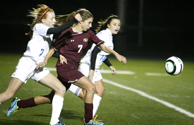 Kathryn Clark of Cape Elizabeth races between Emma England, left, and Marysa Alexander of Falmouth to reach a long ball Tuesday night. Clark caught up to it before it crossed the end line and delivered a pass that resulted in Katherine Briggs’ go-ahead goal in a 3-1 victory.