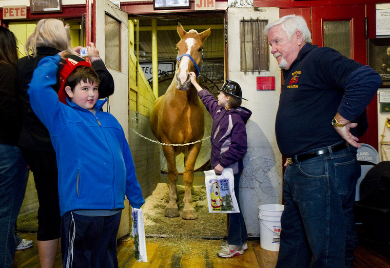 Simon Girard, 7, of Old Orchard Beach poses questions to retired Portland firefighter John “Smokey” Chandler during an open house at the Portland Fire Museum on Saturday. Alison Blow, 10, of Biddeford, pets Jim the horse.