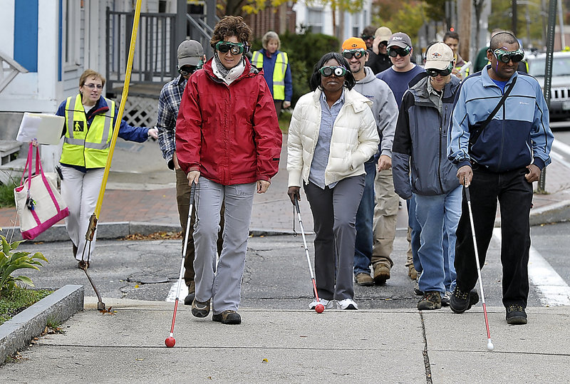 A group of Maine Department of Transportation employees participates in a seminar Tuesday to learn what people with disabilities experience at Portland’s intersections and sidewalks. From left, Sarah Leblanc, Eyitayo Adandekinti and Sammy Samaroo, all assistant engineers, wear vision impairment glasses on Cumberland Avenue.