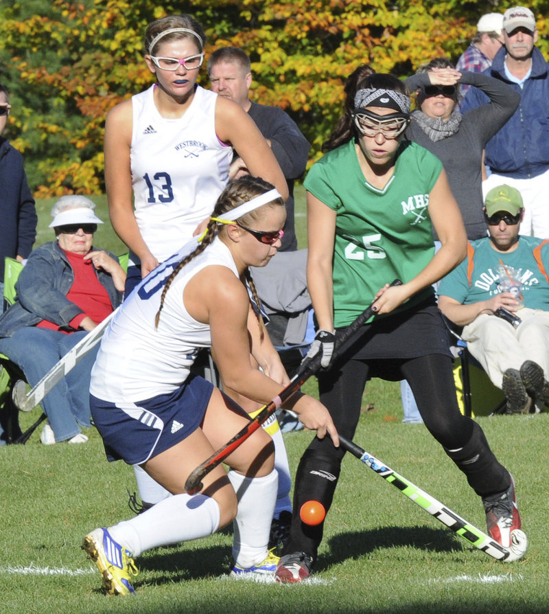 Kerigan Demers of Westbrook, left, competes with Logan Provencher of Massabesic for the field hockey ball in front of Tori Winton of Westbrook.