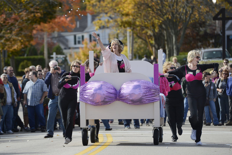 Karen McCloskey of Manchester, N.H., throws candy to spectators as her “Hot Flashes” teammates push their bed during the Bridge to Beach Bed Race in Ogunquit on Sunday. The team was raising money for breast cancer research.