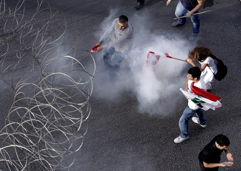 Protesters are enveloped in tear gas as they pull a barbed-wire barrier during clashes after the funeral of Brig. Gen. Wissam al-Hassan in Beirut on Sunday.