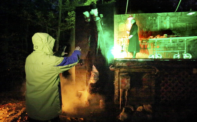 Upside-down reporter Ray Routhier, wearing a Frankenstein costume, gets tips on his role from Cote Hall, 17, left, and Amanda Lilley, 19, on a stage in the background, Oct. 12 at The Gauntlet, a haunted hayride attraction at Harvest Hill Farms in Mechanic Falls. More Maine farms are adding entertainment to supplement their income.