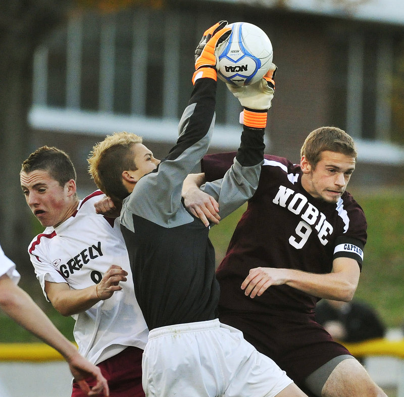 Greely goalkeeper Elijah Leverett pulls down a shot Wednesday night over his teammate, Joe Saffian, left, and Josh Davis of Noble during Greely’s come-from-behind 5-1 victory in a Western Class A boys’ soccer quarterfinal at Cumberland.