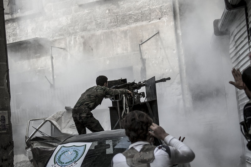 A Free Syrian Army fighter fires as rebels belonging to the Liwa Al Tawhid group carry out a military operation at the Karmal Jabl front line in Aleppo, Syria.