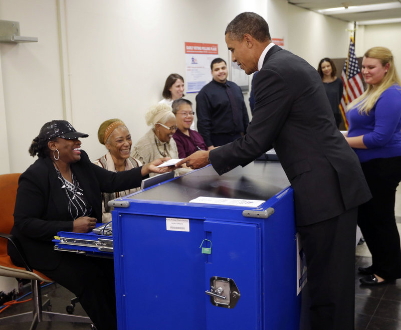 President Obama turns in his ballot receipt to election official Marie Holmes, left, as he prepares to cast his vote at the Martin Luther King Community Center in Chicago.
