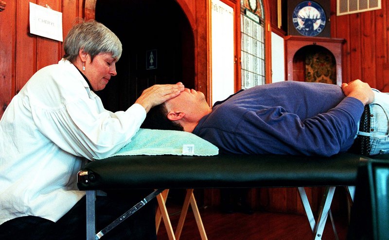 A therapist provides a Reiki treatment at a 1997 Psychic/Holistic Fair in Saco. A Reiki master says many hospitals now offer the “gentle and non-invasive” therapy.