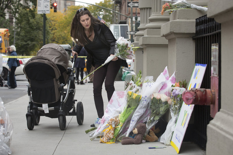A mourner places flowers at a memorial outside the apartment building of the two children allegedly stabbed by their nanny, who then slit her own throat, police said.