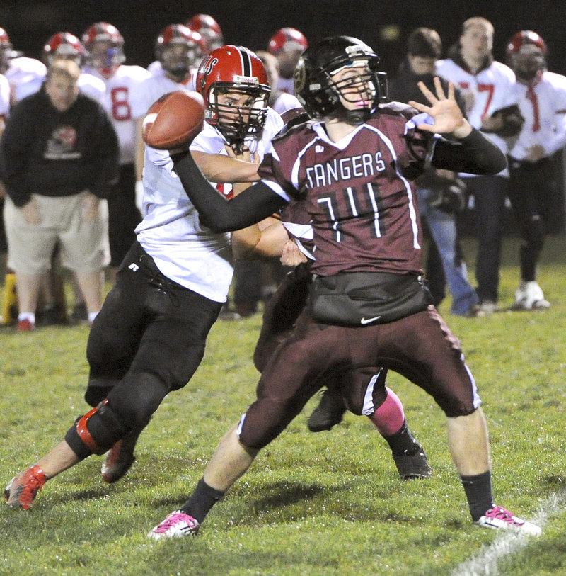 Greely quarterback Drew Hodge tries to unleash a pass as Drew Shelley of Wells closes in during Friday’s Western Class B quarterfinal in Cumberland. Wells pulled out a 9-7 win.