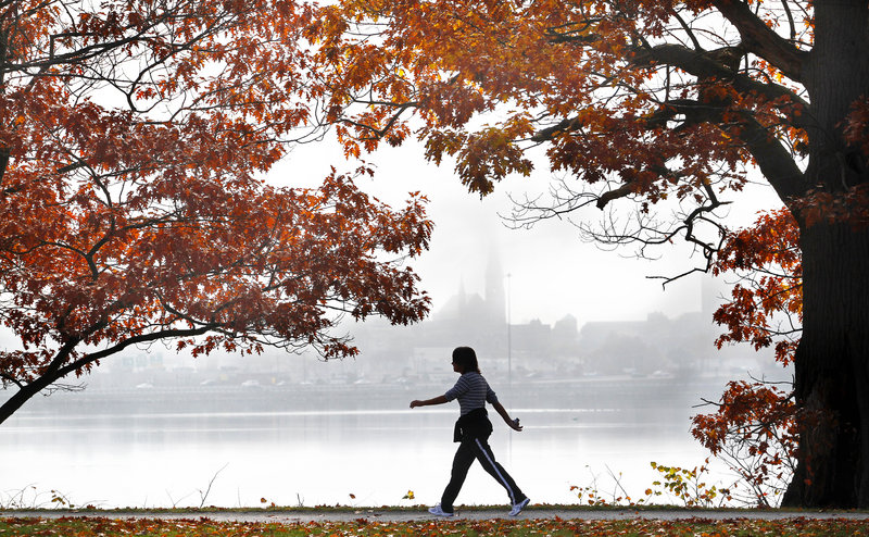 CALM BEFORE THE STORM: A woman walks along Back Cove in Portland on Saturday as morning fog lingers over the city. Expect Sunday to be mostly cloudy with high temperatures in the lower 50s. The weather is expected to deteriorate Monday as Sandy arrives.