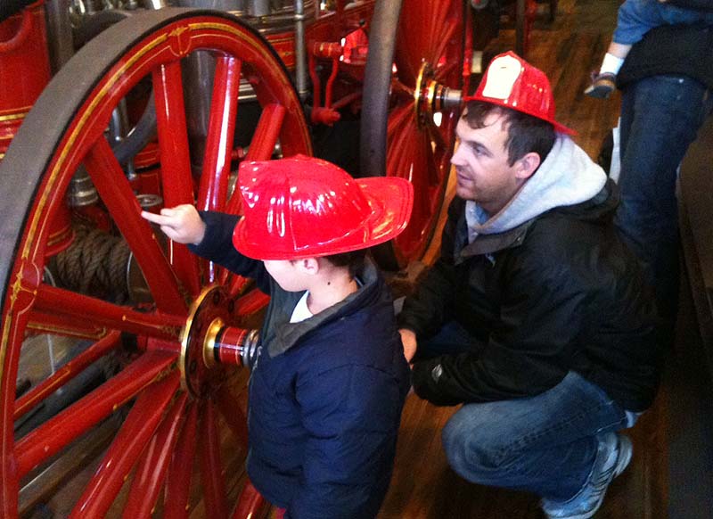 Oscar Goss, 4, and his father, Amos, of Portland check out one of the antique fire engines during an open house at the Portland Fire Museum on Saturday.