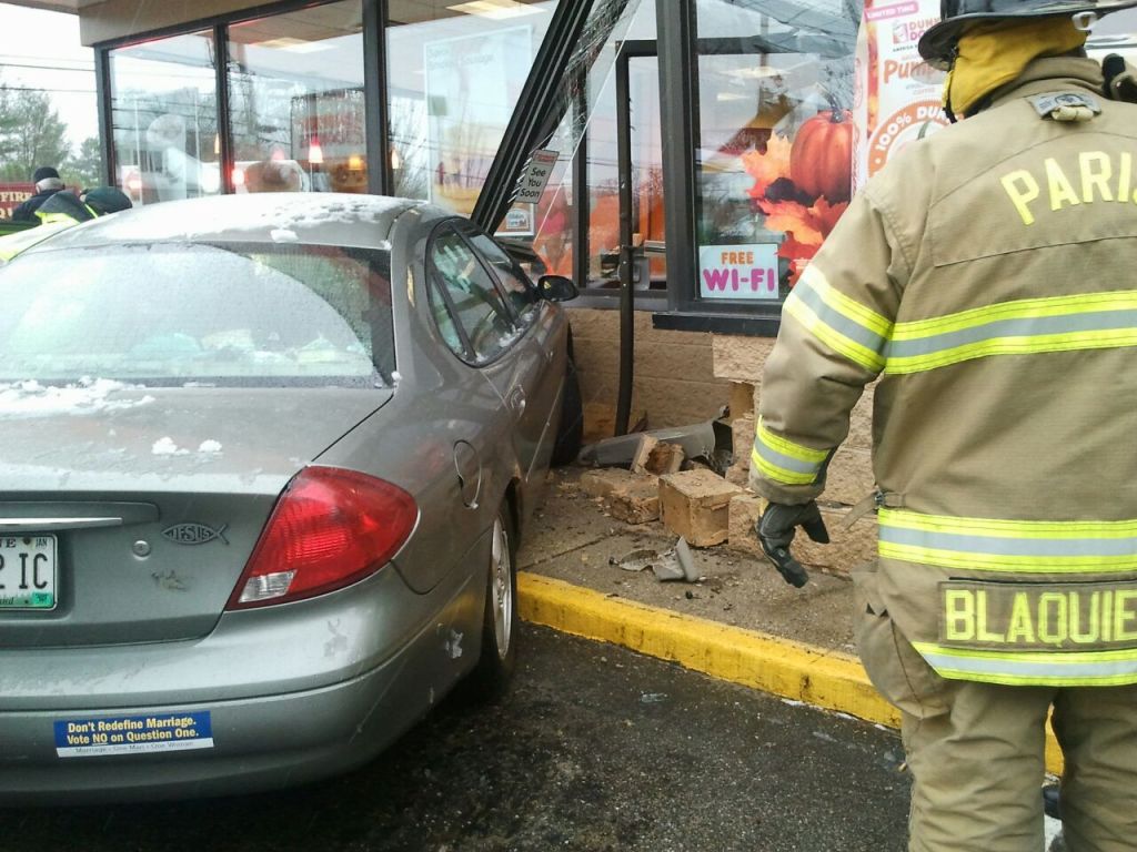 A responder looks over the damage where a car ran into the entrance of the Dunkin' Donuts in Paris, Maine, on Thursday.