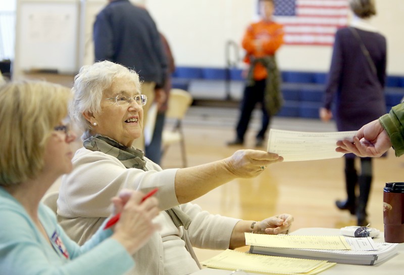 Volunteer Joan Macisso hands a ballot to a voter during voting at the East End Elementary School Tuesday morning in Portland on November 6, 2012. Tim Greenway/Staff Photographer
