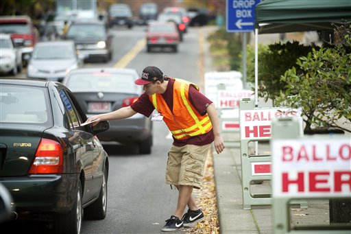 Clark County elections official Miguel Rivera takes ballots from motorists outside the Clark County Elections office Tuesday Nov. 6, 2012 in Vancouver, Wash. (AP Photo/The Columbian, Troy Wayrynen)