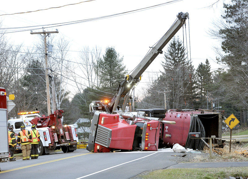 Workers try to upright a Troiano Waste Services truck on Route 237 in Gorham on Tuesday. The truck was loaded with 15 cubic yards of liquid waste chicken and raw chicken parts.Police blamed driver inattention for the crash.