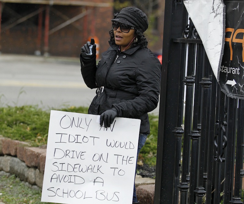 Shena Hardin holds up a sign to serve a highly public sentence Tuesday, Nov. 13, 2012, in Cleveland, for driving on a sidewalk to avoid a Cleveland school bus that was unloading children. A Cleveland Municipal Court judge ordered 32-year-old Hardin to serve the highly public sentence for one hour Tuesday and Wednesday. (AP Photo/Tony Dejak)