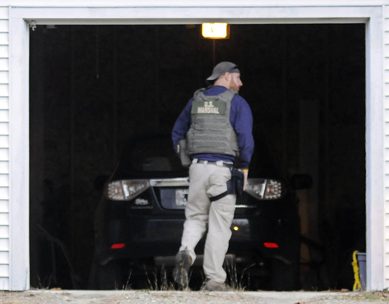 A U.S. Marshal Service investigator searches the garage at the residence of Barbara Cameron, the ex-wife of fugitive James Cameron, Tuesday in Hallowell. Authorities are continuing to hunt for Maine’s former top drug prosecutor.