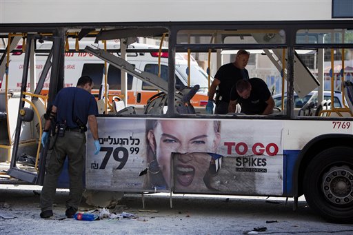 Israeli police officers examine a blown-up bus in Tel Aviv Wednesday. The blast near Israel's military headquarters wounded 27 people.