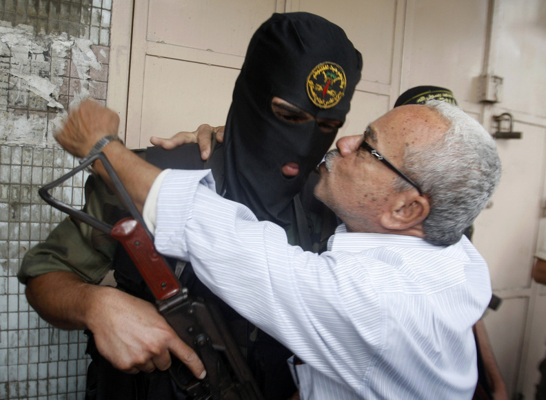 A Gaza man hugs a Palestinian militant after a press conference in Gaza City on Thursday. Gazans are celebrating a cease-fire agreement reached with Israel to end eight days of fighting.