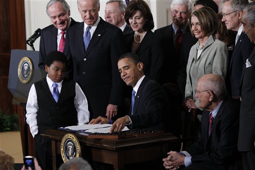 President Obama reaches for a pen to sign the health care bill into law at White House on March 23, 2010.