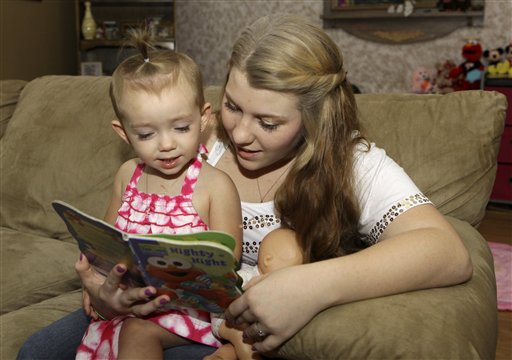 Kali Gonzalez reads to her daughter Kiah, 2, at their home in St. Augustine, Fla., recently. A new report by the National Women's Law Center says offering pregnant teens extra support would ultimately save taxpayers money by helping them become financially independent and not dependent on welfare.