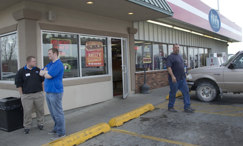 An unidentified customer walks out of the Trex Mart convenience store, right, while manager Chris Nauerz, left, and son of the owner Baron Hartell stand outside, in Dearborn, Mo., Thursday, Nov. 29, 2012. Lottery officials confirmed Thursday that one of two winning Powerball tickets sold before Wednesday's drawing was bought at a Trex Mart convenience store in Dearborn. (AP Photo/Orlin Wagner)