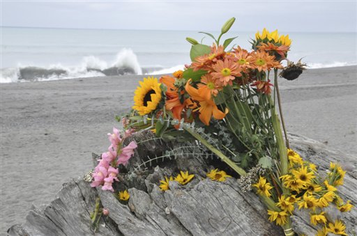 Flowers rest on a drift log yards from the breaking surf of the Big Lagoon beach near Trinidad, Calif., where a family that tried to rescue their dog were swept out to sea.