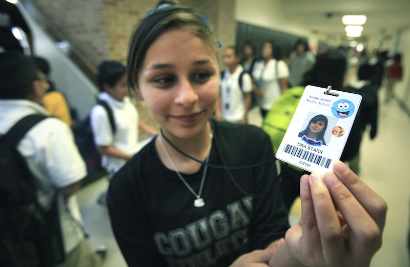 In this Oct. 1, Tira Starr, an 8th grader at Anson Jones Middle School, shows her ID badge as students change classes in San Antonio, Texas. The San Antonio school district's website was hacked over the weekend to protest its policy requiring students to wear microchip-embedded cards tracking their every move on campus. A teenager purportedly working with the hacker group Anonymous said in an online statement that he took the site down because the Northside school district "is stripping away the privacy of students in your school." All students at John Jay High School and Anson Jones Middle School are required to carry identification cards embedded with a microchip. They are tracked by the dozens of electronic readers installed in the schools' ceiling panels. (AP Photo/San Antonio Express-News, Bob Owen) RUMBO DE SAN ANTONIO OUT; NO SALES