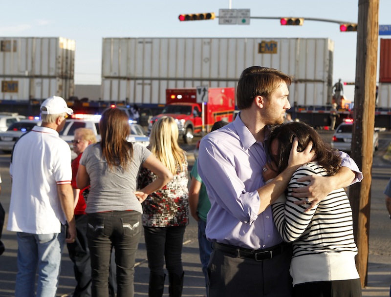 Bystanders react as emergency personnel work the scene where a trailer carrying wounded veterans in a parade was struck by a train in Midland, Texas, Thursday, Nov. 15, 2012. "Show of Support" president and founder Terry Johnson says there are "multiple injuries" after a Union Pacific train slammed into the trailer, killing at least four people and injuring 17 others. (AP Photo/Reporter-Telegram, James Durbin) MRT;accident;wreck;crash;armed forces