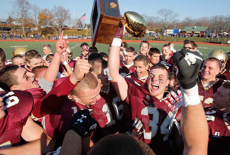 Senior Nick Kenney of Thornton Academy hoists the championship trophy after the Trojans defeated Lawrence 37-23 Saturday to win the state Class A football championship at Fitzpatrick Stadium in Portland.