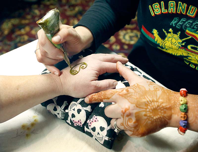 Artist Amy Walker creates henna art on a client's hand during Psychic Sunday at the Fireside Inn and Suites in Portland.