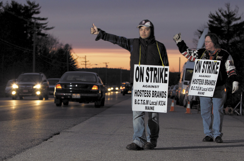 Striking workers Nam Phan, left, and Randy Goodwin picket outside a Hostess Brand plant Friday, in Biddeford.