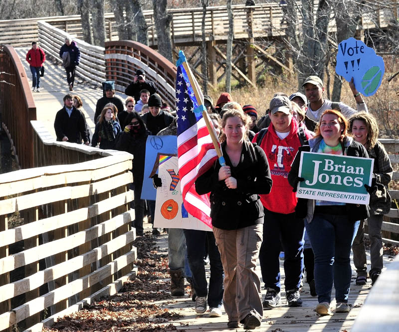Unity College student Jena Zoller carries the American flag while leading 50 students and staff who marched along the CommUnity Trail from campus to town to vote on Tuesday.