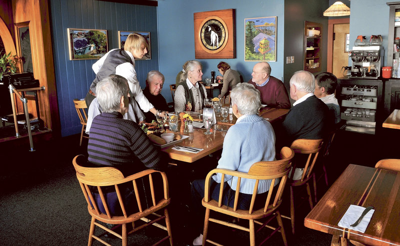 Waitress Sarah Dutil serves meals during lunch at The Last Unicorn restaurant in Waterville. This large group dined at the popular eatery during a birthday celebration for Tom Tietenberg, at head of table on right.