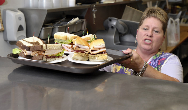 Goldie Gordios calls out sandwich orders inside the Full Belly Deli at Pine Tree Shopping Center in Portland. The tray includes the Fall Fowl, Hamwich and Perkey Turkey.