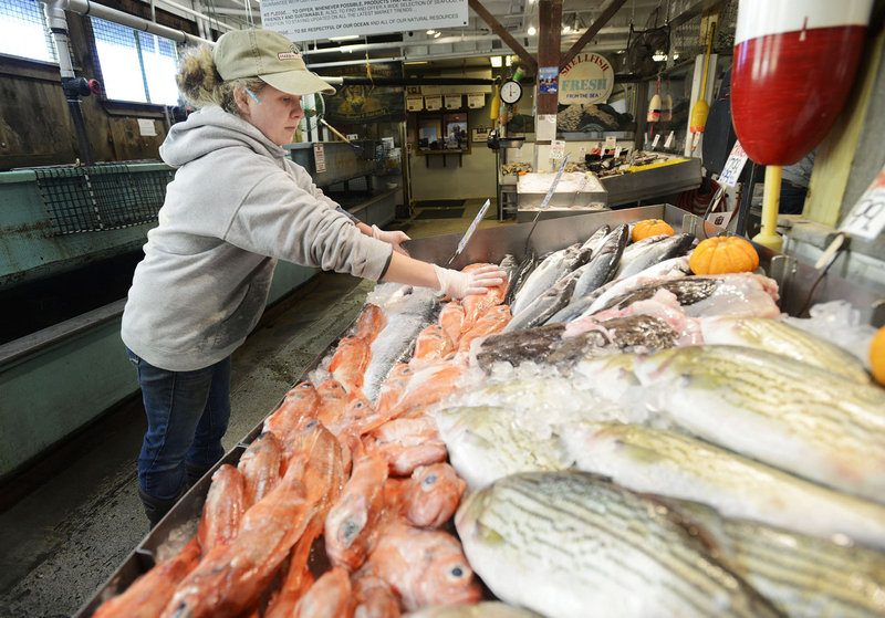 Lauren MacVane stocks the display case at Harbor Fish Market in Portland Thursday. Fish and lobster prices are down due to the lack of demand from buyers in the areas where Sandy knocked out power and did major damage.