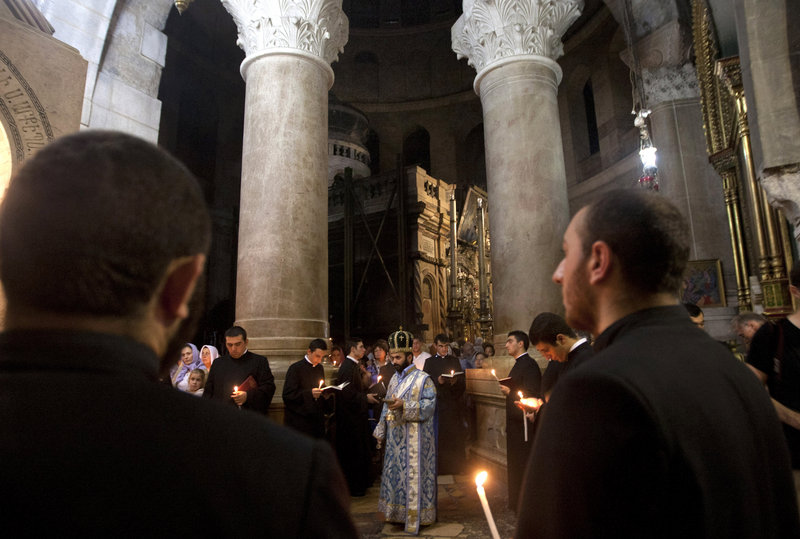 Clergymen hold candles inside the Church of the Holy Sepulchre in Jerusalem’s Old City on Friday. A clergyman from the church built on the site where Jesus Christ is said to have been crucified said Friday that its bank account has been frozen as the result of a water bill dispute.
