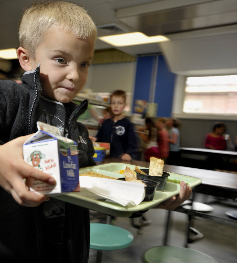 Tyler Hussey, 6, heads to his seat with pita chips, carrot slaw and hummus to go with his pizza and milk.