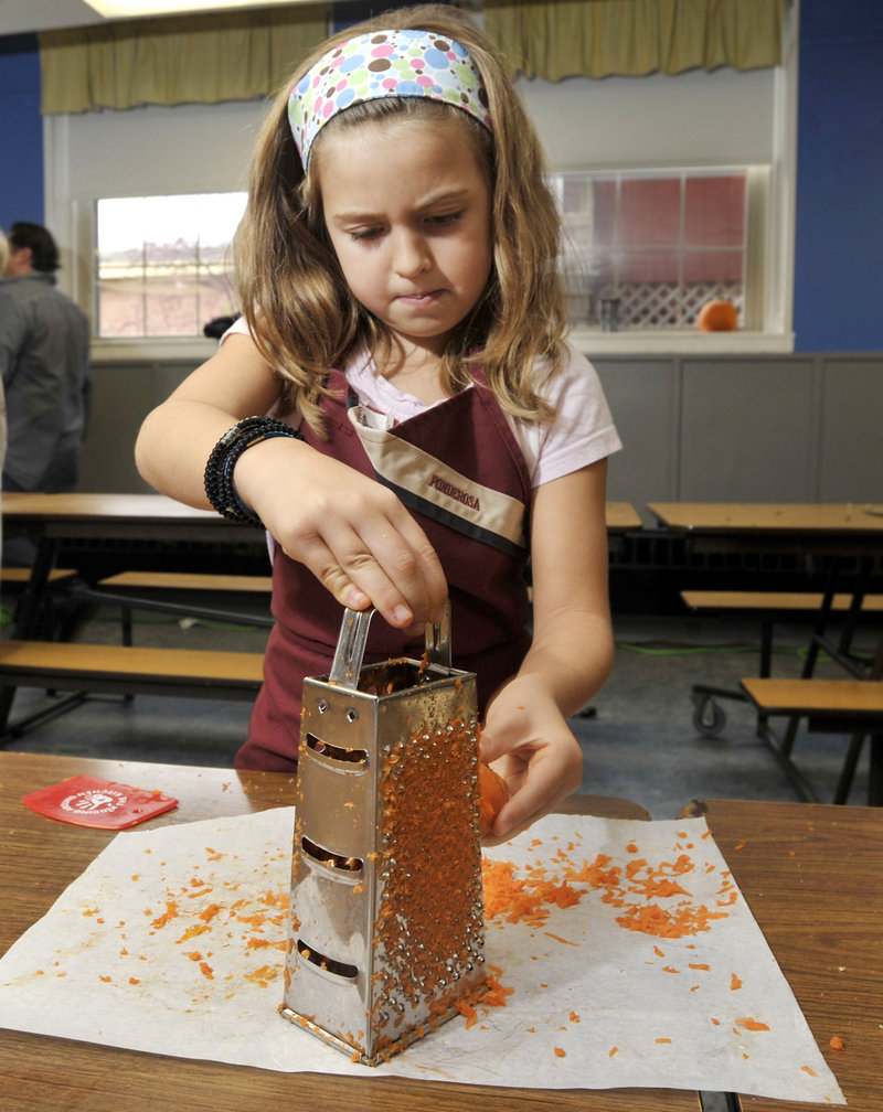 Abby Simonelli, a second-grader at South Berwick Central School, helps make carrot slaw during a recent lesson on healthy eating.