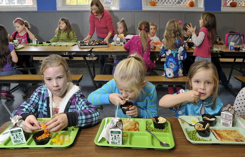 First-graders, from left, Abby Blethroade, Hannah Doram and Addison Brown eat lunch that includes carrot slaw, hummus and pita chips the students in South Berwick helped to prepare. The schoolchildren voted the hummus their favorite.