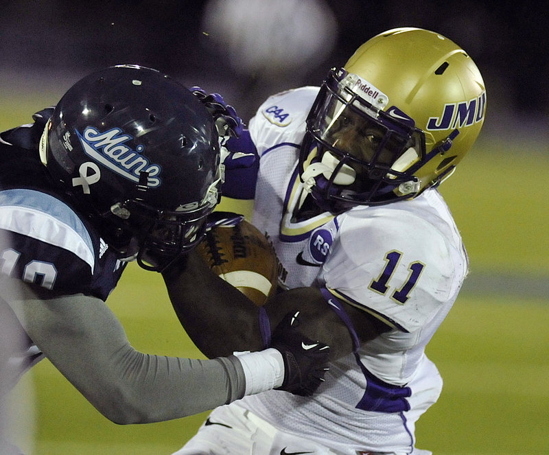 James Madison tailback Dae’Quan Scott tries to eacape the grasp of Maine defender Axel Ofori during Saturday’s game in Orono.