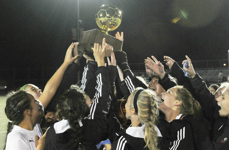 Falmouth players hold the Gold Ball aloft, again, after capturing their third straight Class B girls’ soccer state championship Saturday with a 2-1 victory over Hermon.