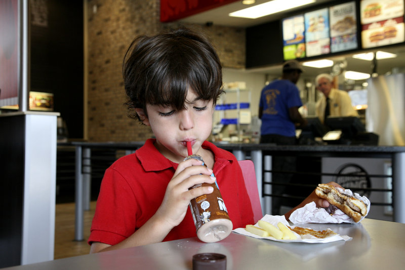 A boy eats a hamburger at a Burger King in Miami in 2011. In a recent column, food writer Avery Yale Kamila unfairly criticizes hamburger, chicken, eggs, peanut butter and myriad other foods as products of the “industrial food system,” a reader says.