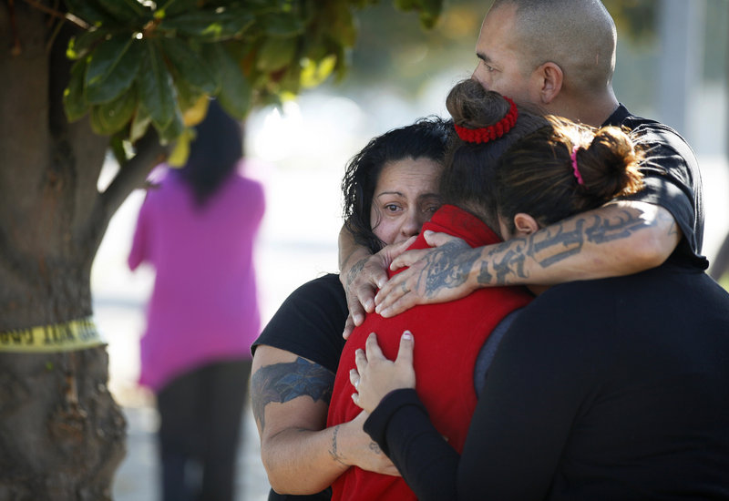Three women and a man hug outside the police perimeter in central Fresno where a shooting occurred at a workplace Tuesday. A parolee who worked at a California chicken processing plant opened fire at the business, killing two people and wounding three others.