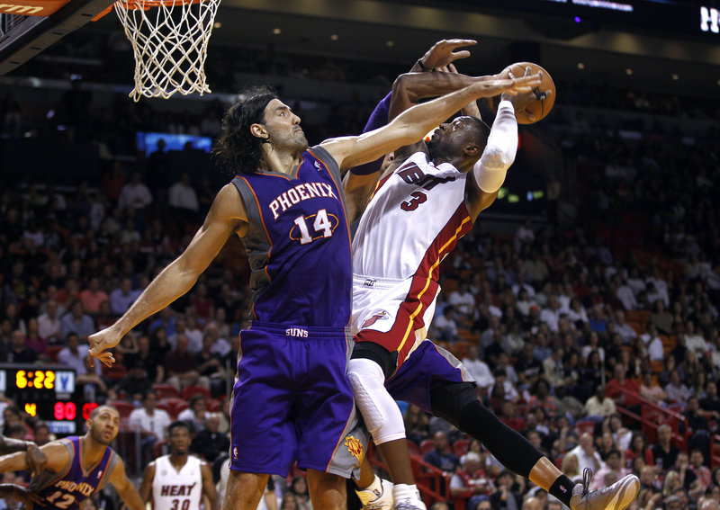 Dwyane Wade of the Miami Heat tries to get a shot over the Phoenix Suns’ Luis Scola on Monday night. Long a defense-first team, the Heat have so far been far from the stingy outfit that won the NBA title last season.